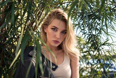 Blonde model in a leather jacket among tall grasses