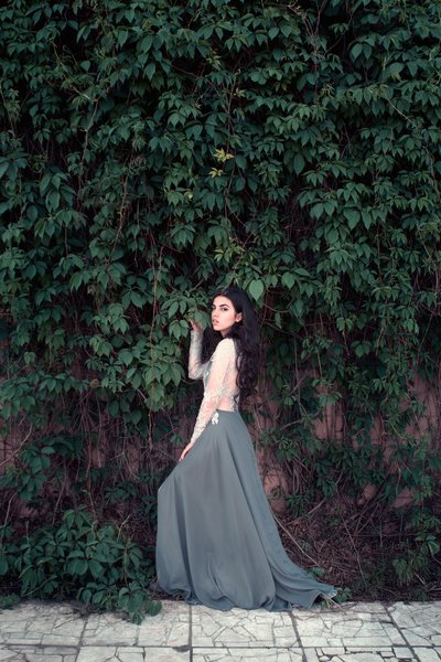 Standing gown, overgrown stone wall behind
