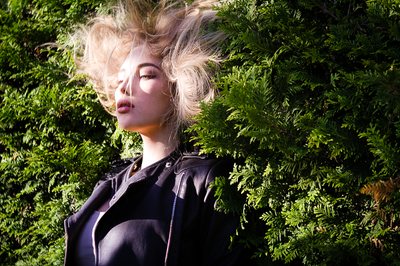 Wind-blown hair against green leaves