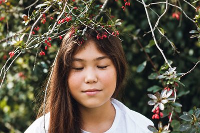 Girl among branches with her eyes closed
