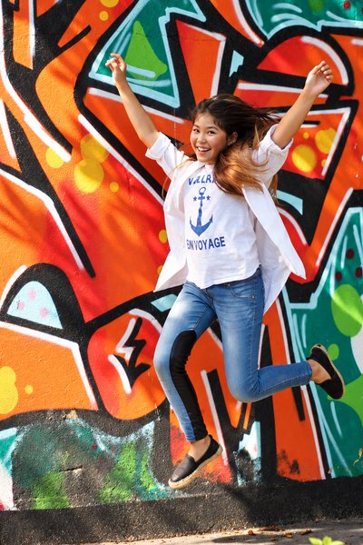 Girl jumping in front of a graffiti wall