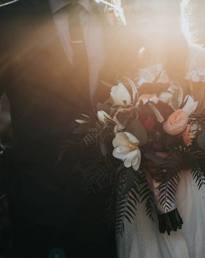 Bride and groom under a veil in a wheat field at sunset